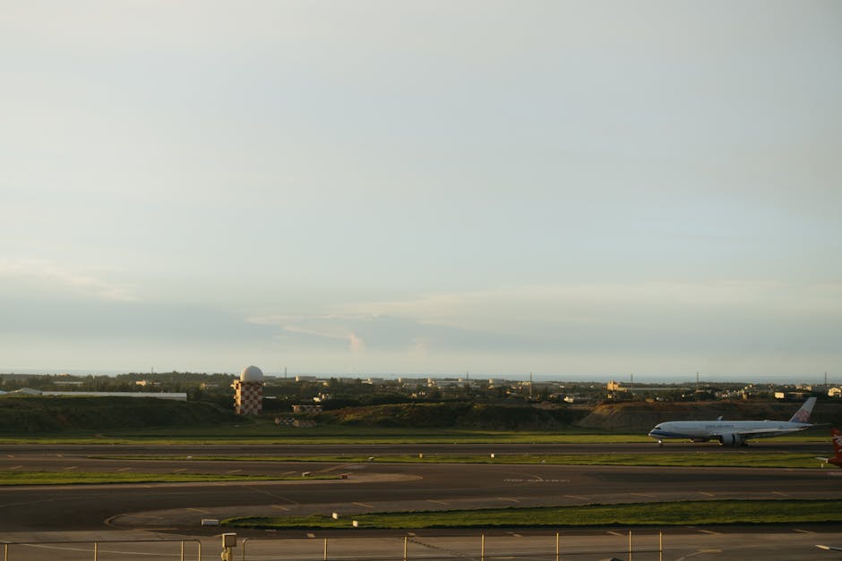 An airplane on the runway during sunset with a distant cityscape view.