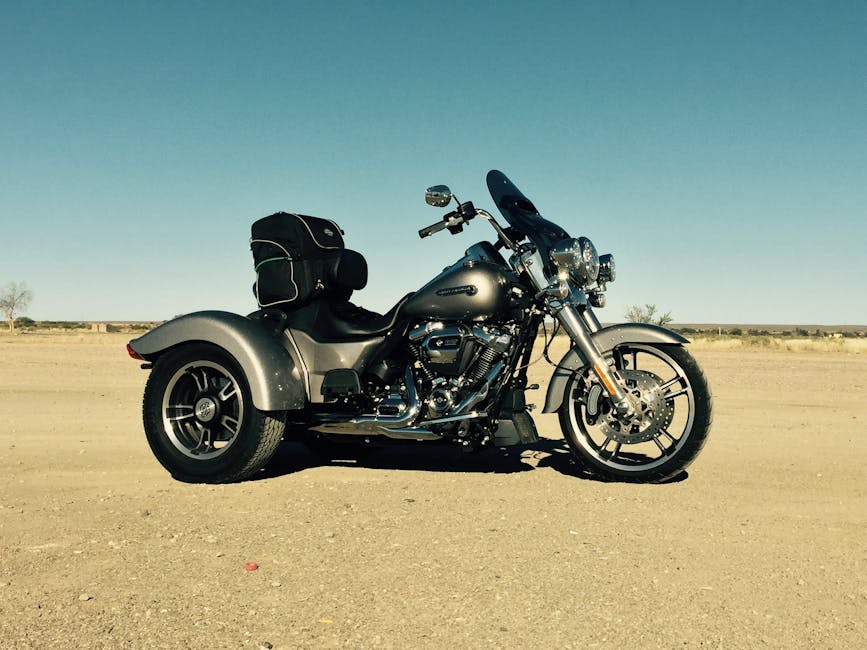 A gunmetal grey Harley trike parked on a desert road in Namibia under a clear sky.