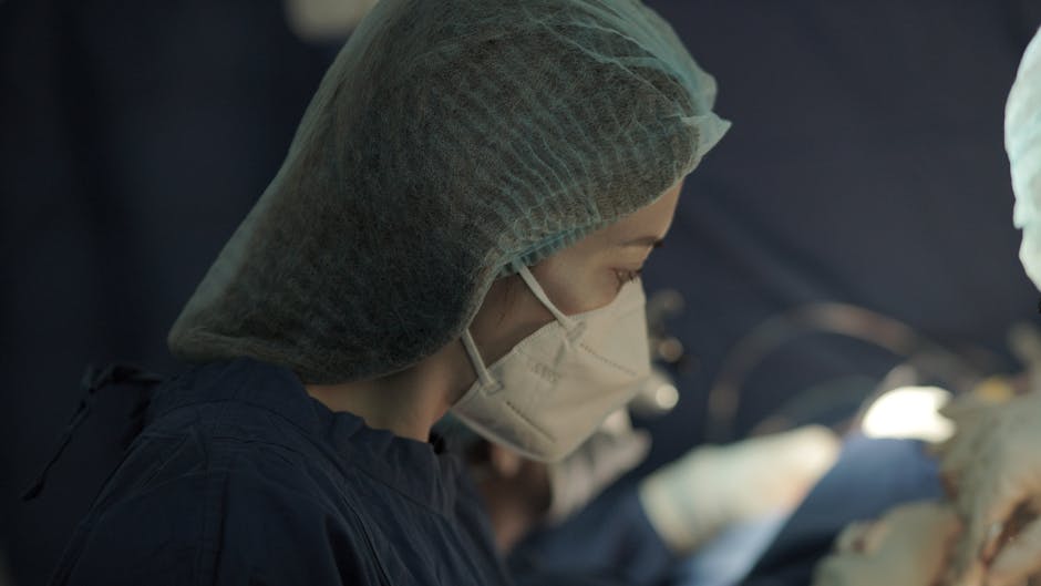 Focused female surgeon in mask during a critical operation. Focused female surgeon in mask during a critical operation.