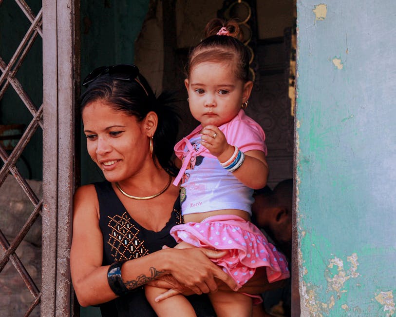 A smiling mother holds her daughter while standing in a doorway. A smiling mother holds her daughter while standing in a doorway.