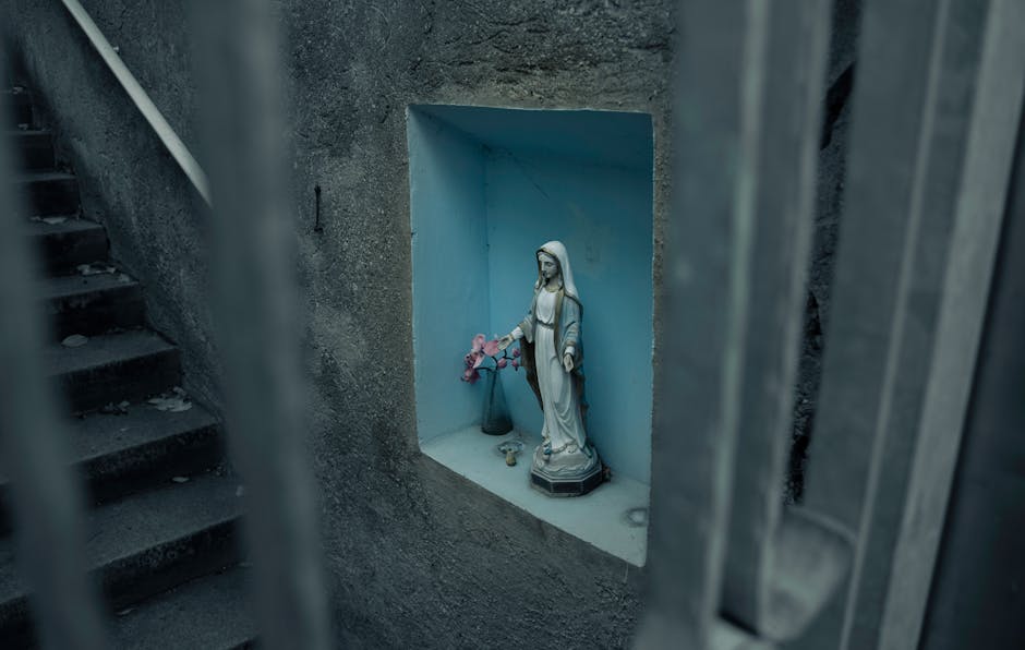 A statue of the Virgin Mary in a wall niche with flowers in Stuttgart, Germany. A statue of the Virgin Mary in a wall niche with flowers in Stuttgart, Germany.
