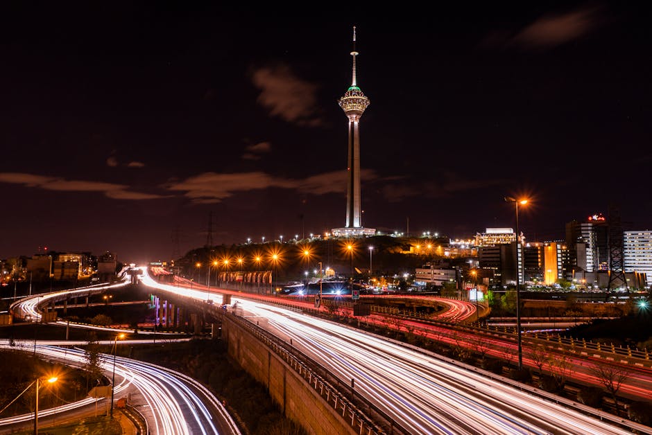 Stunning night view of Tehran's Milad Tower with light streaks from highway traffic.