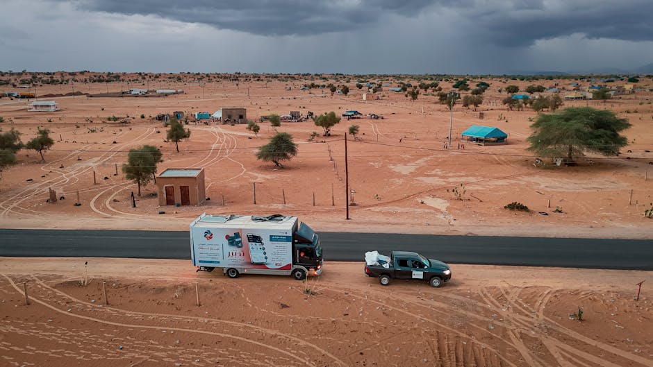 A scenic aerial view of vehicles on a road in a barren desert landscape, highlighting arid conditions.