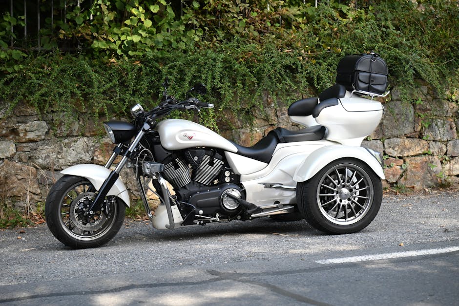 A sleek white trike motorcycle parked against a stone wall with lush greenery background. A sleek white trike motorcycle parked against a stone wall with lush greenery background.