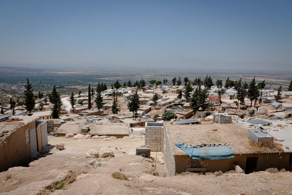 A scenic view of a rural settlement in Idlib, Syria surrounded by trees and landscape.