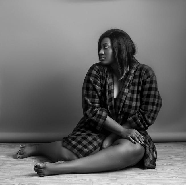 Captivating black and white portrait of a woman in plaid robe sitting and looking away thoughtfully. Captivating black and white portrait of a woman in plaid robe sitting and looking away thoughtfully.
