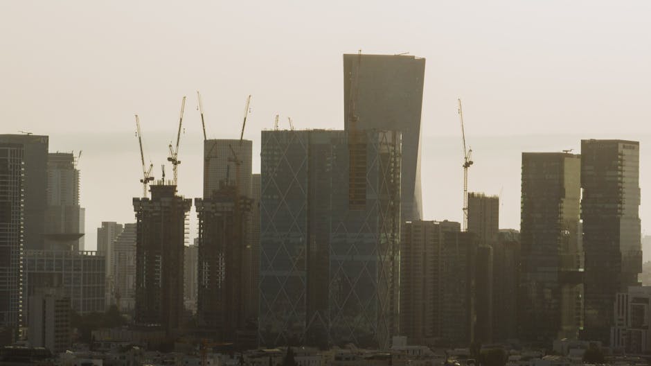 A view of Tel Aviv's cityscape featuring skyscrapers and construction cranes under a hazy sky.